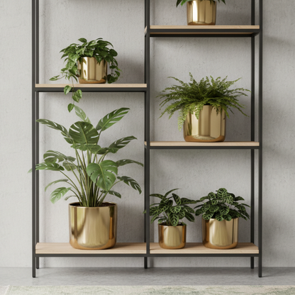 une étagère moderne avec des caches pots cylindriques dorés et plantes vertes variées